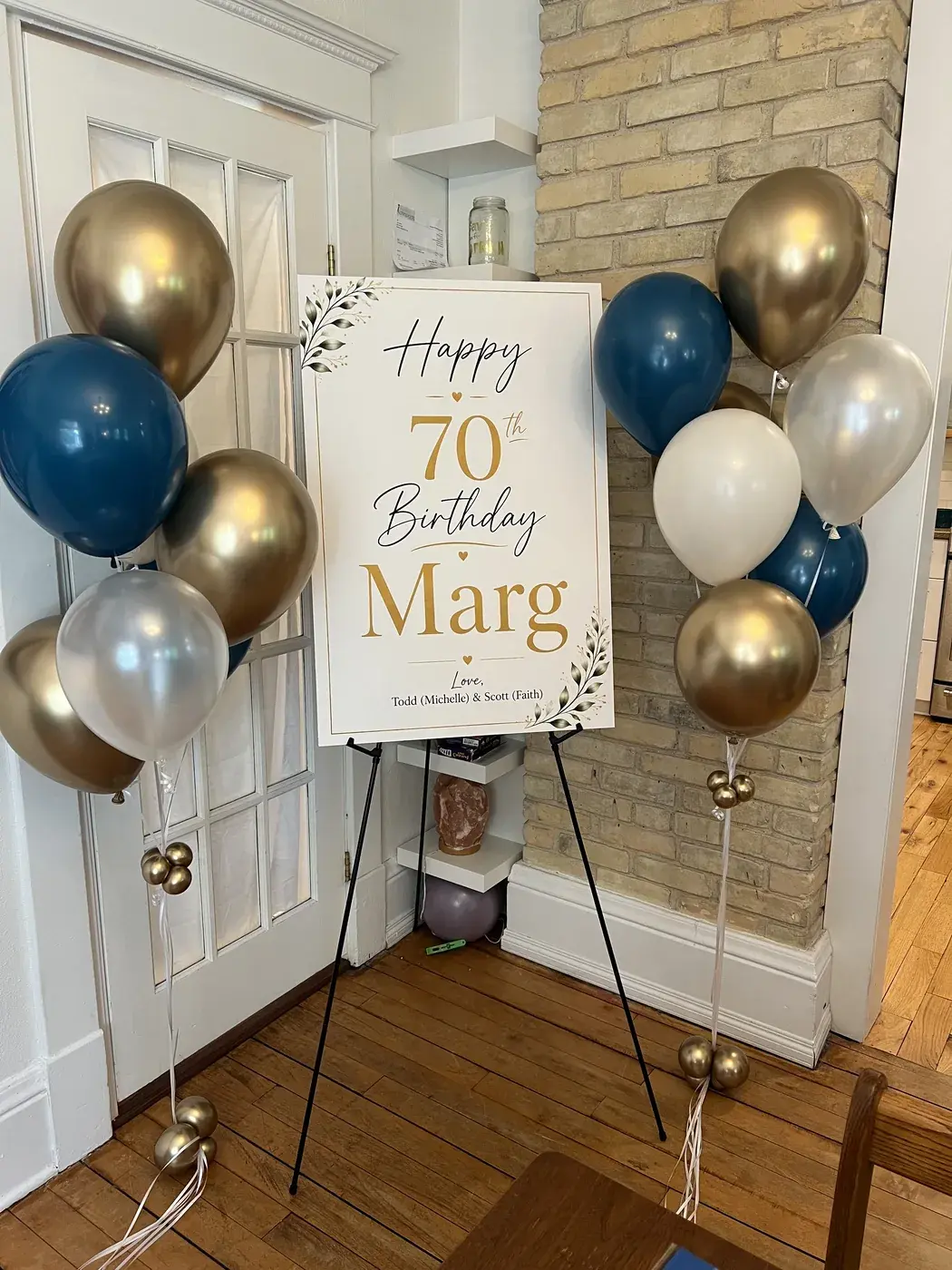 Navy, gold and chrome balloon bouquets flanking a 70th birthday sign on an easel