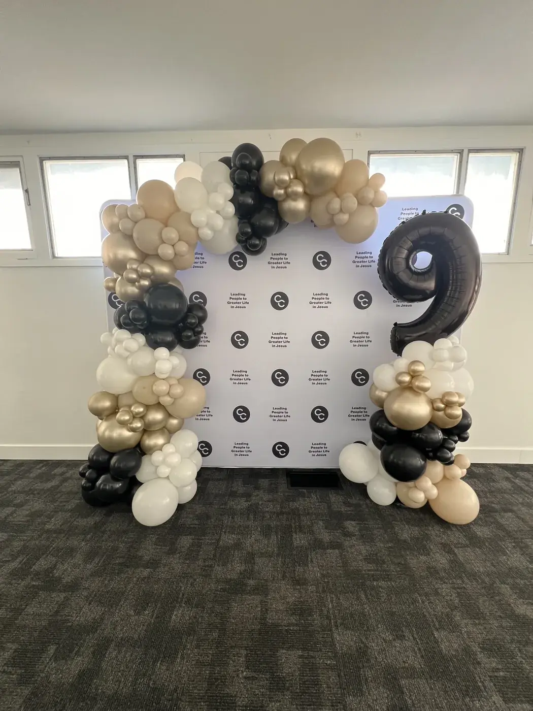 Branded step and repeat with an oversized black nine in cream, gold and black