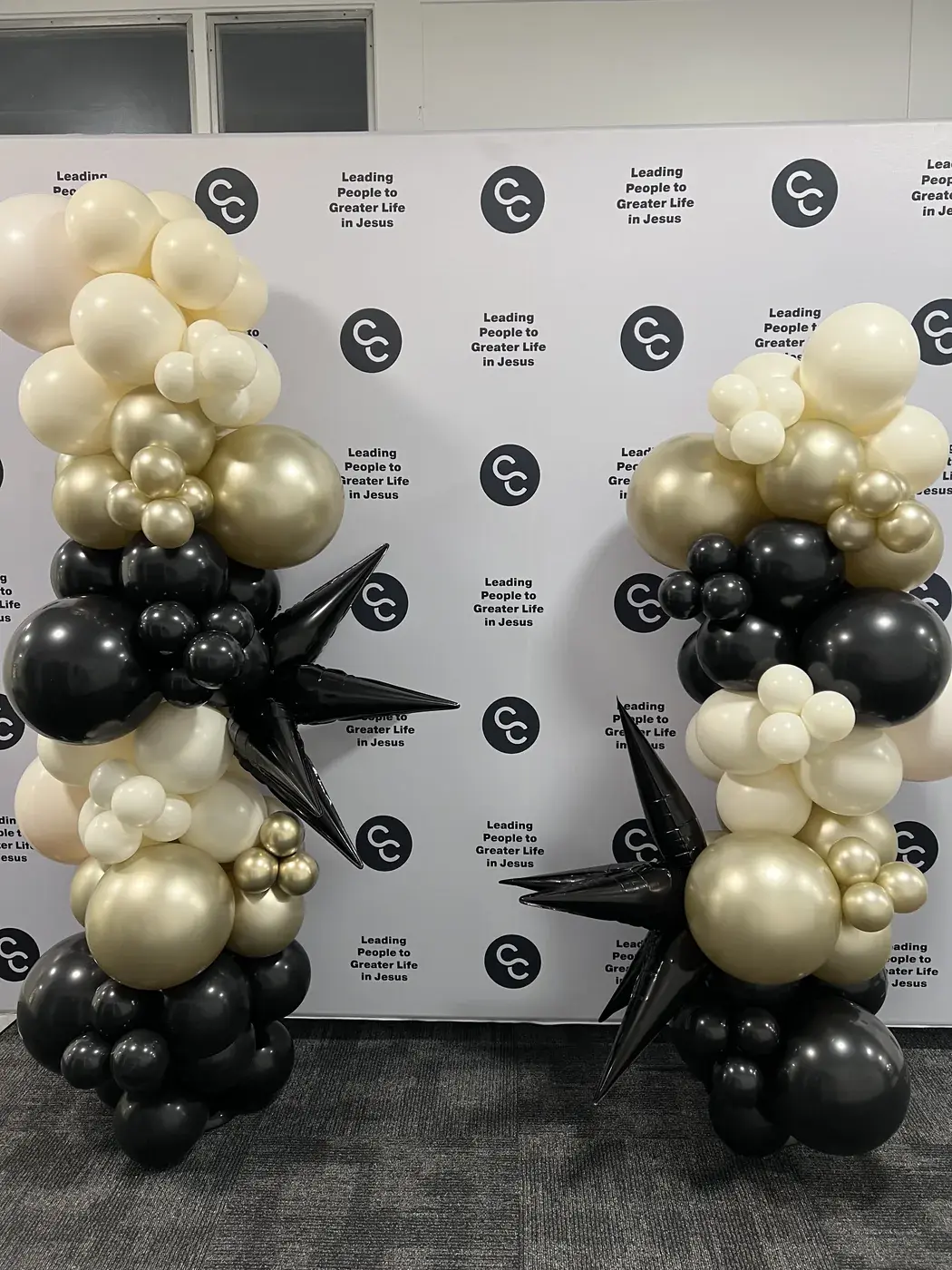 Branded church step and repeat wall flanked by cream, gold and black columns