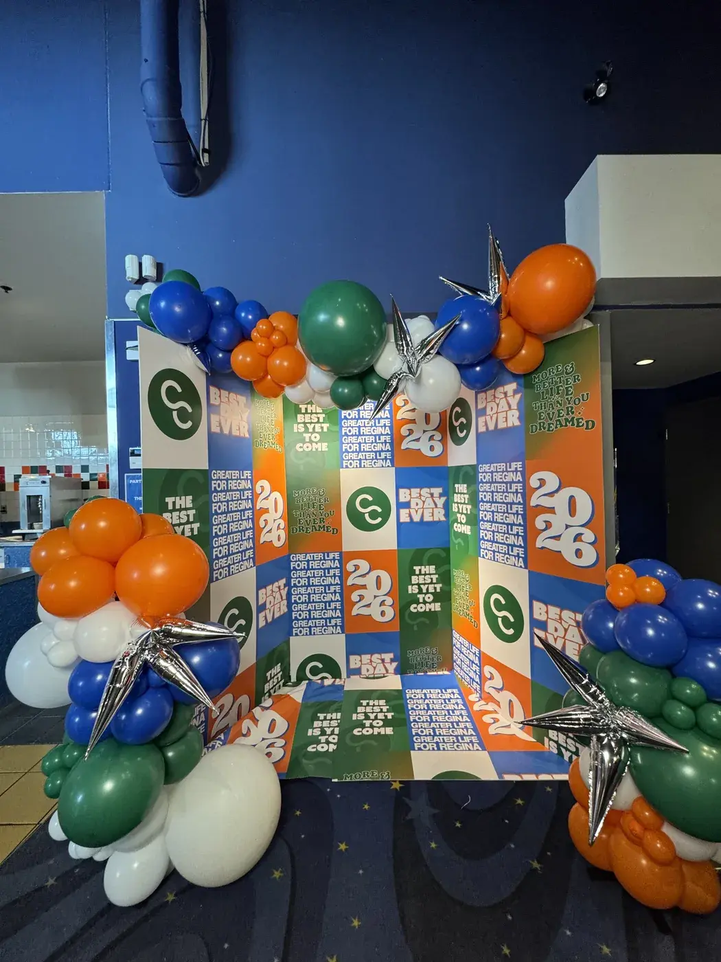 Printed summer programme backdrop with a blue, green and orange garland and star bursts