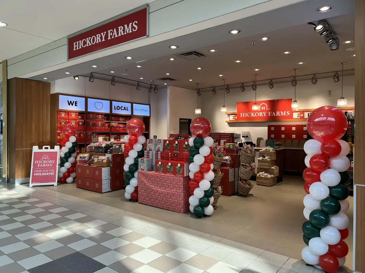 Red, green and white balloon columns framing a Hickory Farms shopfront