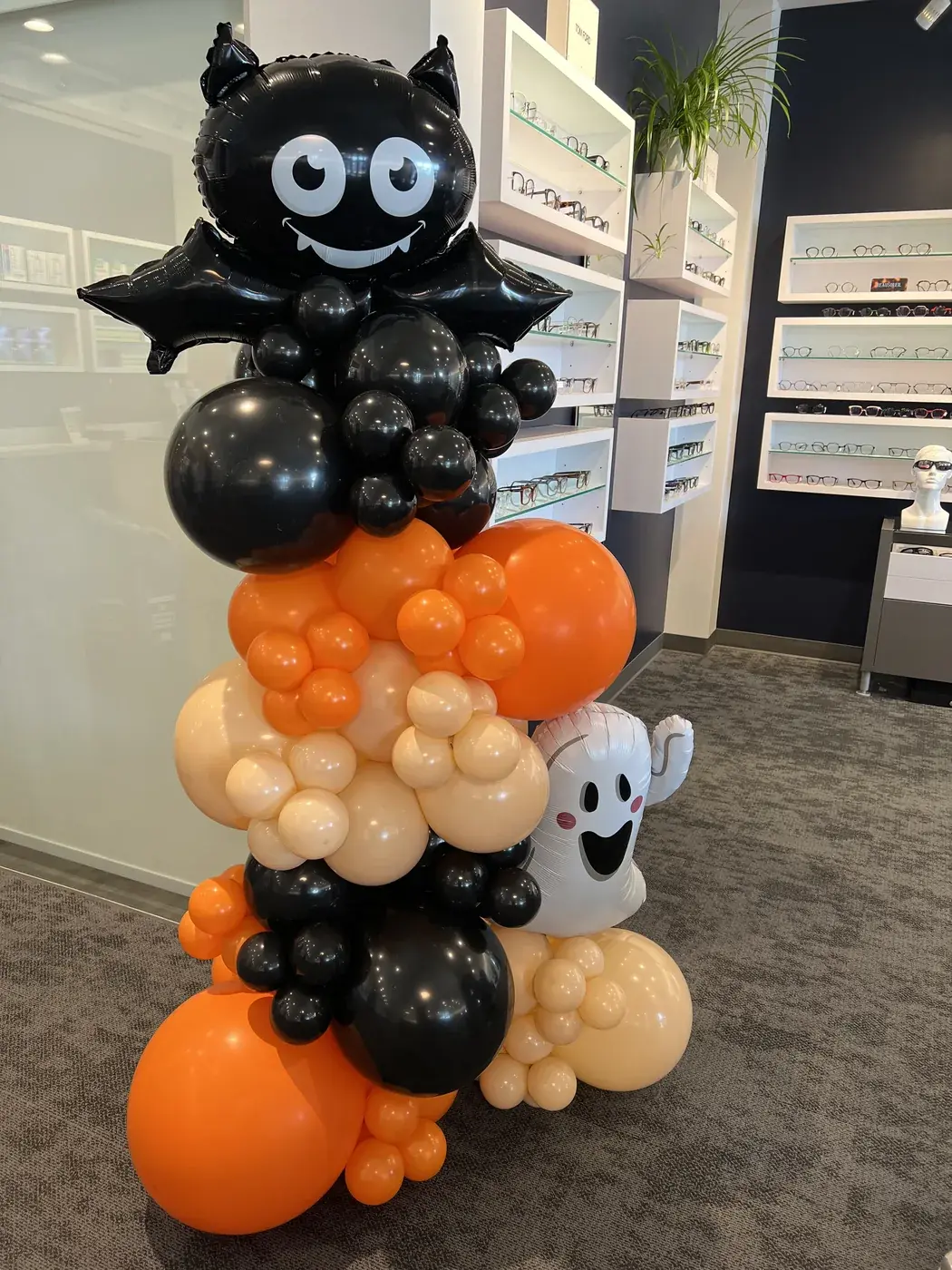 Halloween column in black, orange and cream topped with a bat, with a ghost balloon