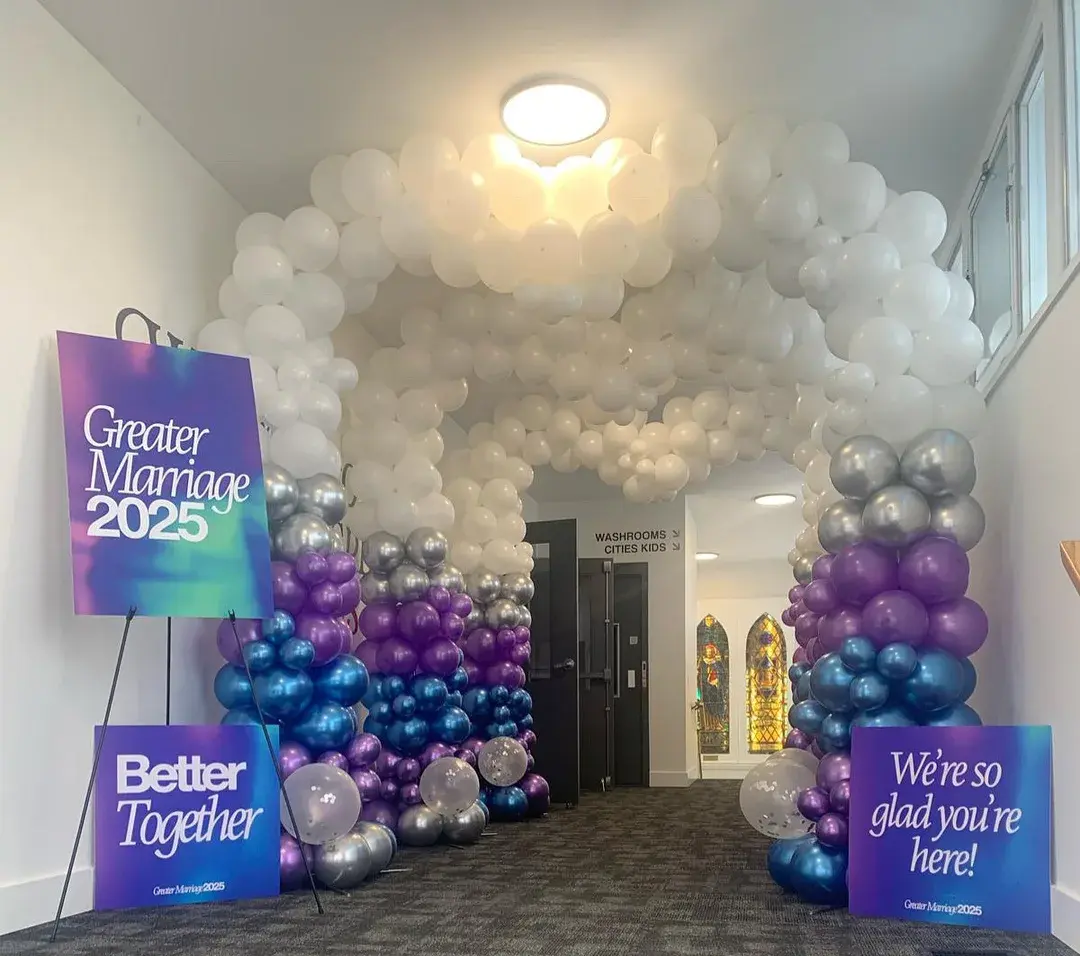 White, purple and silver balloon archway over a conference entrance