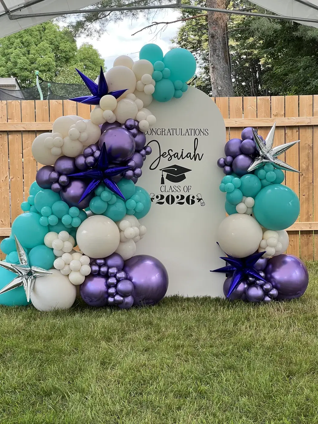 Custom painted arch backdrop with personalised vinyl lettering and a teal, purple and cream garland