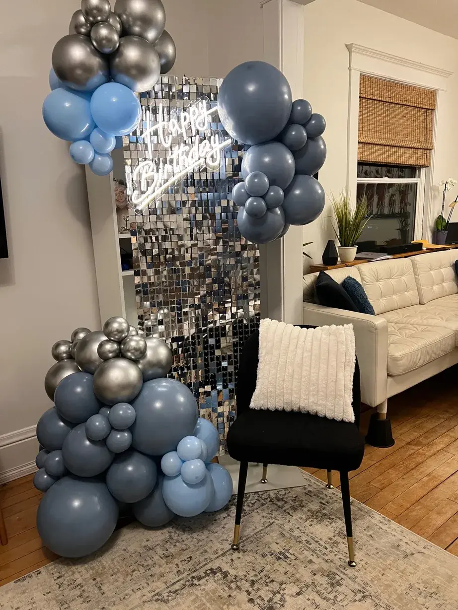 Blue and silver balloon garland framing a disco shimmer wall