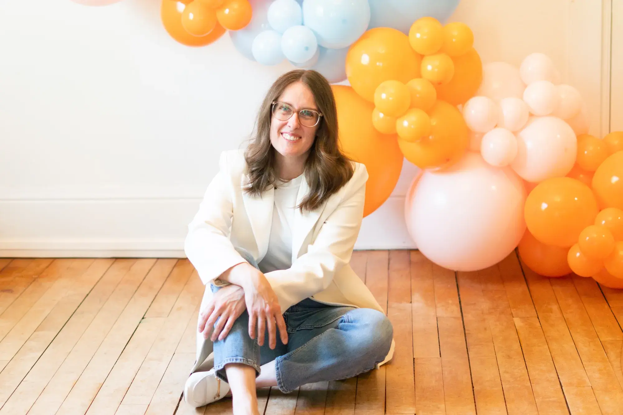Rebecca sitting in front of an orange and peach balloon garland